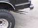 1989 Ford Bronco - A close-up view of the rear of a black 1989 Ford Bronco, showing the tire, exhaust, and body details.