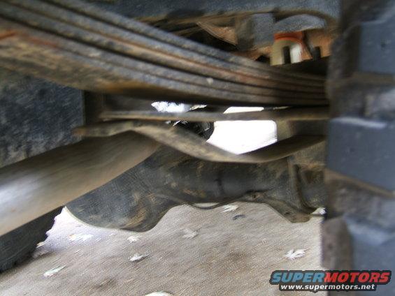 Close-up of leaf springs and exhaust pipe on a vehicle's undercarriage