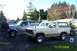 1996 Ford Bronco - Two Ford Broncos, a tan model and a silver model, are parked in a driveway on a sunny day.