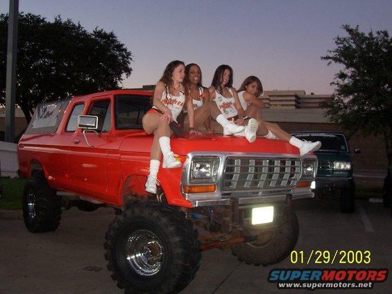 Red lifted 1978 Ford Bronco with four women on hood, front view