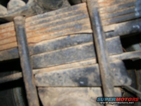 Leaf springs with U-bolts, showing rust and dirt