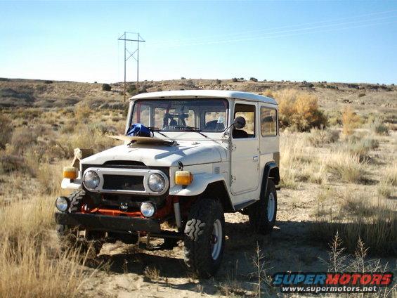 1976 Toyota Land Cruiser parked on dirt road in dry, grassy landscape with power lines in background
