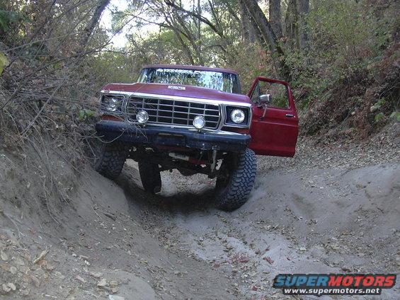 Red 1979 Ford F-Series truck with open door on a dirt trail