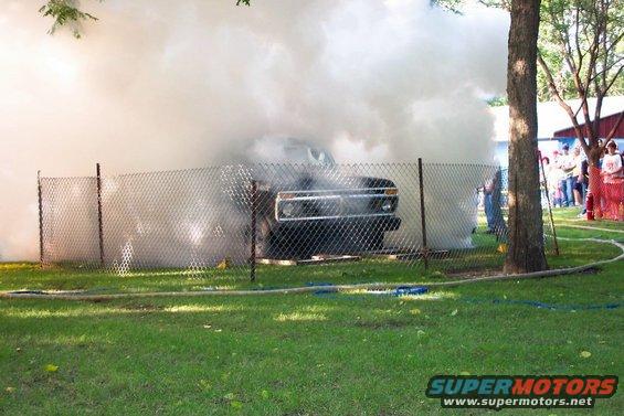 Truck engulfed in smoke behind a chain-link fence