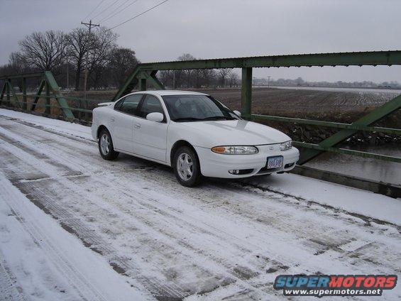 White 1999 Oldsmobile Alero parked on a snow-covered bridge