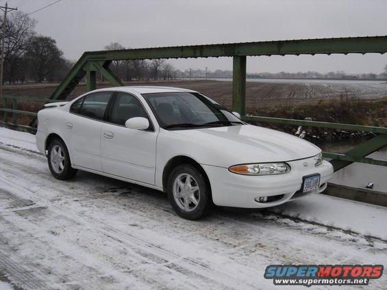 White 1999 Oldsmobile Alero parked on a bridge with snow on the ground