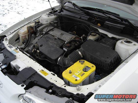 1999 Oldsmobile Alero engine bay showing the Twin Cam engine and a yellow Optima battery