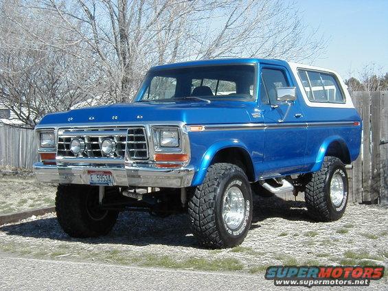 Blue 1978 Ford Bronco with a white hardtop, lifted suspension, and chrome wheels parked outdoors