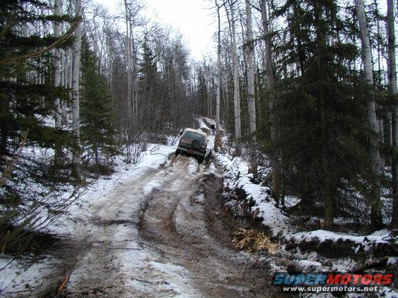 SUV on a difficult muddy and snowy road in a forest