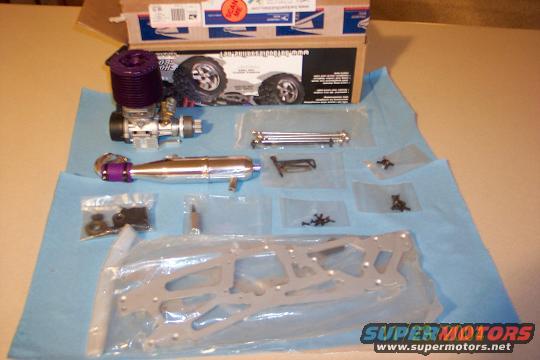 RC car engine, exhaust, and chassis parts laid out on a blue cloth