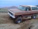 1978 Ford Bronco - A brown 1978 Ford Bronco navigates a dirt track in a hilly, arid landscape.