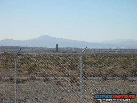 Airport with control tower, planes on tarmac, and mountains in distance