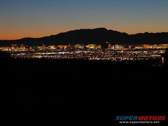 Las Vegas skyline at dusk with mountains in the background and a watermark at the bottom right
