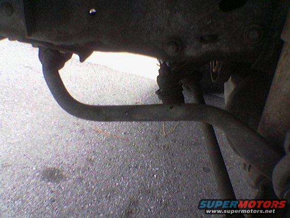 Close-up of a curved metal bar, likely a sway bar, attached to a vehicle's undercarriage