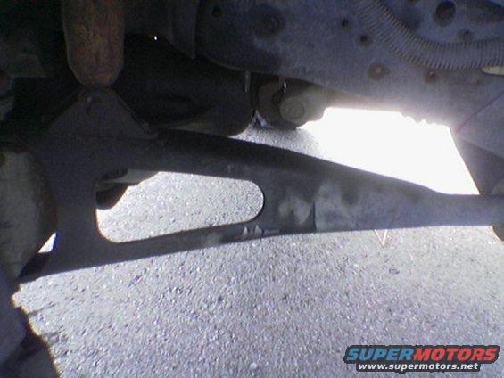 Underside of a vehicle showing suspension parts and a driveshaft