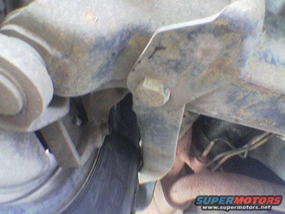 Undercarriage view of a tire and suspension, showing rust and a bolt