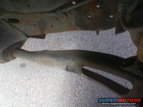 Underside of a vehicle showing rusty frame and exhaust pipe