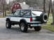 1994 Ford Bronco - This two-tone Ford Bronco is parked on a paved surface with a red barn in the background.