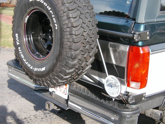 Rear view of a Ford Bronco showing spare tire mounted on bumper, taillight, and trailer hitch