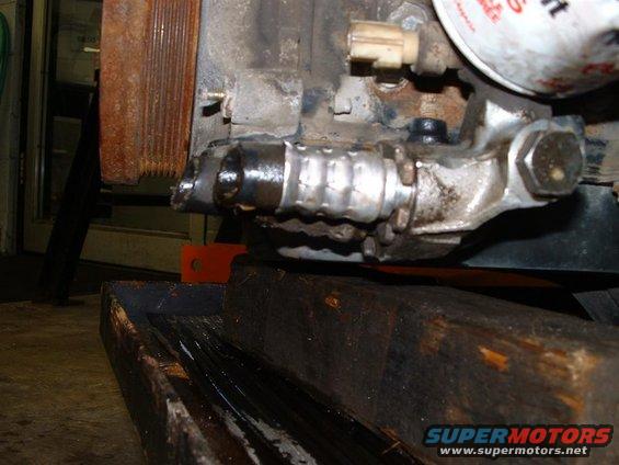 Close-up of a vehicle's engine oil cooler line, possibly leaking, with a drain pan underneath