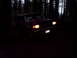 1988 Ford Bronco - A red SUV with its headlights on is parked in a dark forest at night.