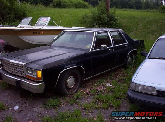 Black sedan parked next to a light blue car and a boat