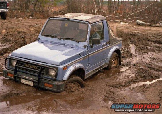 Blue Suzuki Samurai stuck in mud, front grille has 'SUZUKI' text and license plate '237981'
