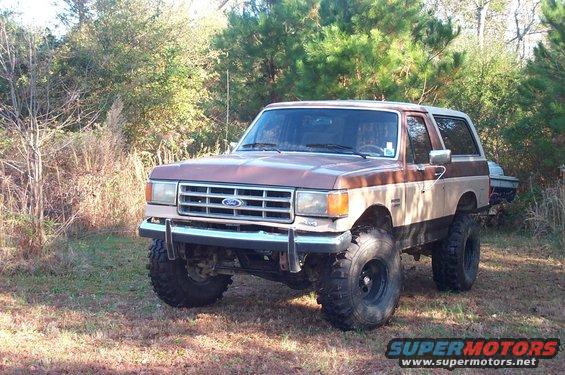 Brown and tan 1987 Ford Bronco with lifted suspension and large tires parked outdoors
