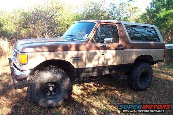 Brown and tan Ford Bronco with lifted suspension and large tires parked outdoors