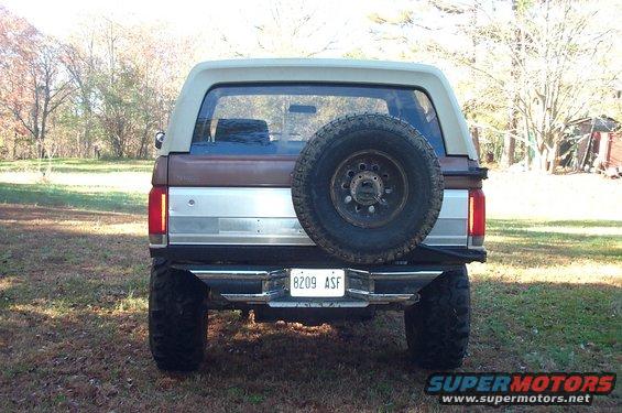 Brown and tan Ford Bronco rear view with spare tire mounted on the back. License plate reads 8209 ASF