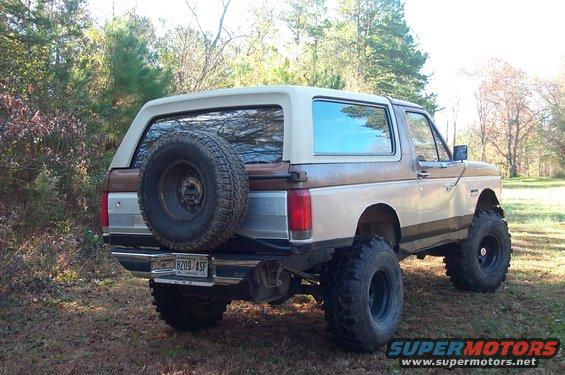 Lifted 1987 Ford Bronco, rear view, with external spare tire and brown/tan paint