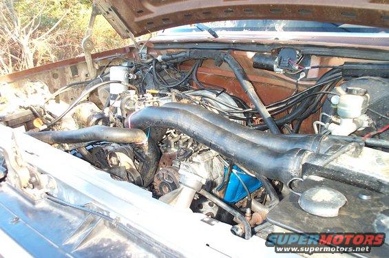 Engine bay view showing a V8 engine with intake pipes and wiring
