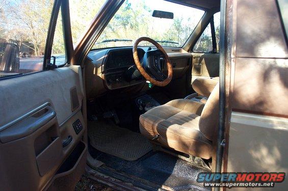 1987 Ford Bronco interior showing tan seats, dashboard, steering wheel, and door panel