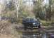 1988 Ford Bronco - A black SUV with a lifted suspension navigates through a muddy, water-filled path in a wooded area.