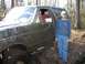 1988 Ford Bronco - A muddy Ford Bronco is seen in a wooded area with a person standing beside it.