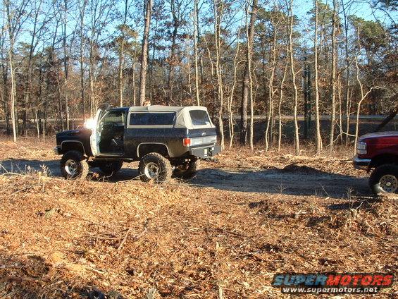 Black 1989 Chevrolet Blazer with lifted suspension and soft top in a wooded area