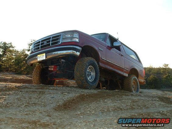 Red lifted 1992 Ford Bronco on rocky terrain