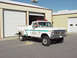 1973 Ford F-250 - White 1973 Ford F-250 utility truck parked in front of a garage bay.