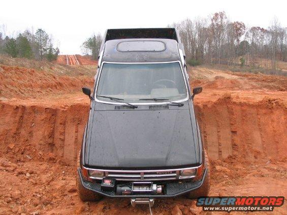 Black Toyota truck stuck in dirt ditch, front view with winch