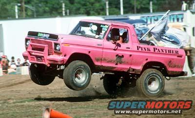 Pink pickup truck with 'Pink Panther' on side, mid-air during event