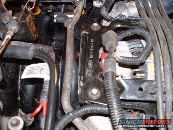 Close-up of engine bay with wiring, hoses, and alternator visible. Part number 13-5514-01M stamped on bracket