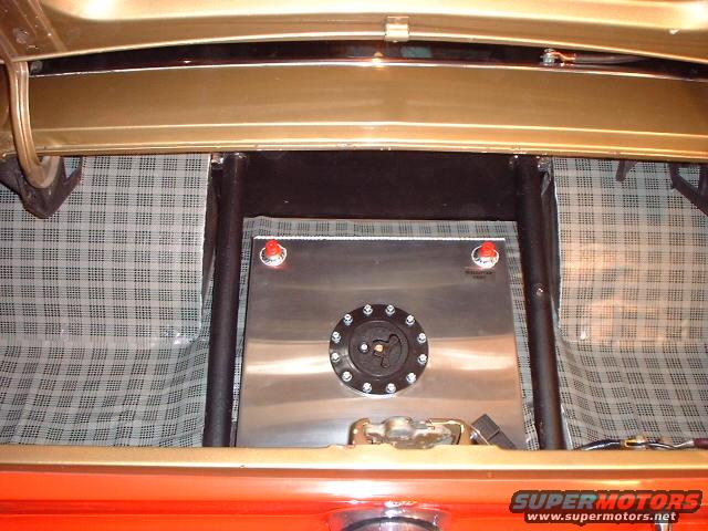 Trunk interior with custom aluminum fuel cell and roll cage tubing. Plaid liner visible