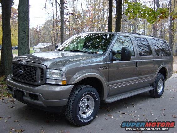 Gray Ford Excursion parked outdoors with trees in the background