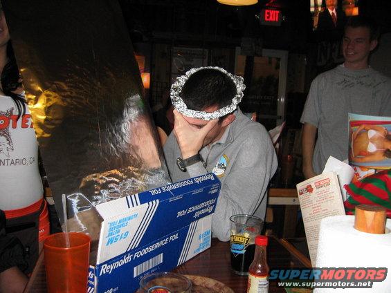 Guy with foil on head, another guy in gray shirt, and a woman in a Hooters shirt at a table with Reynolds Foodservice Foil