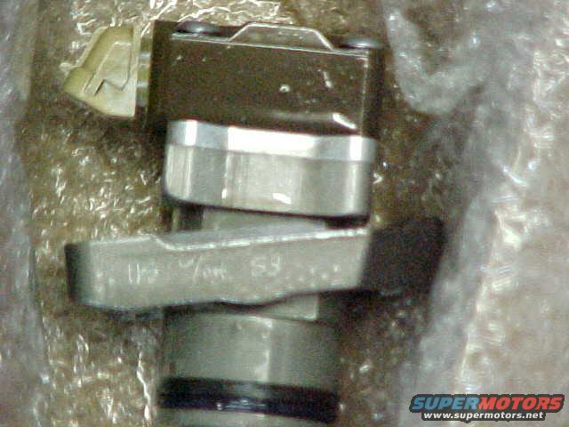 Close-up of a metal automotive sensor with a plastic connector. Text is visible on the metal part