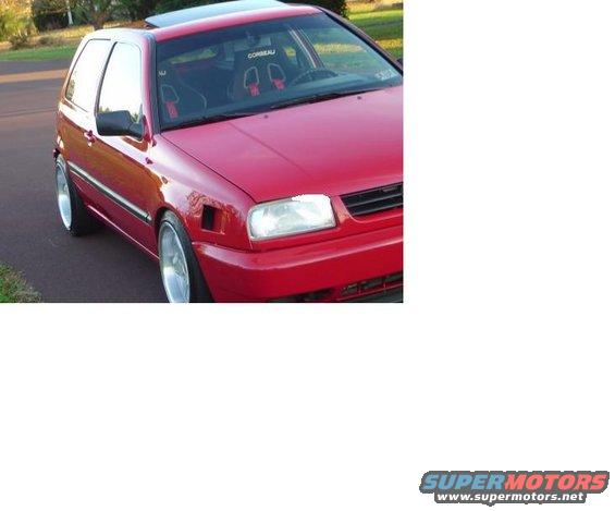 Red hatchback with aftermarket seats and wheels, viewed from the front three-quarter angle