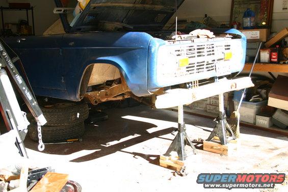 Blue SUV on jack stands in a garage, hood up, front end exposed