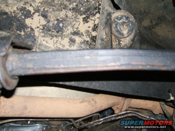 Underside of a vehicle showing exhaust pipe and frame components. Some dirt and rust are visible
