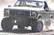 1984 Ford Bronco - Ford Bronco with large tires driving off-road.