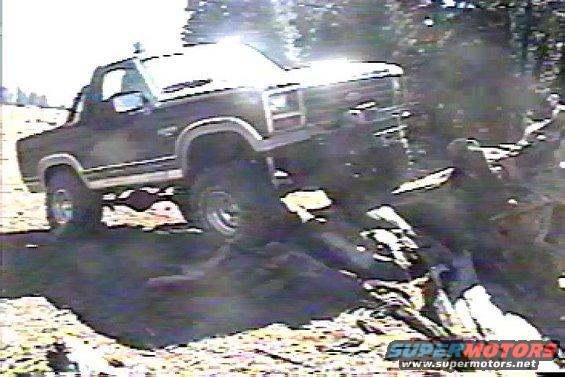 1980s Ford Bronco climbing over logs and dirt